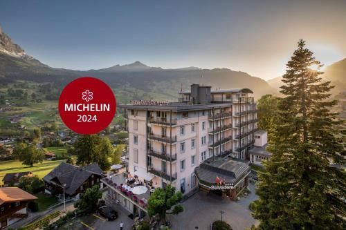 Exterior view of a Swiss hotel with mountains in the background.